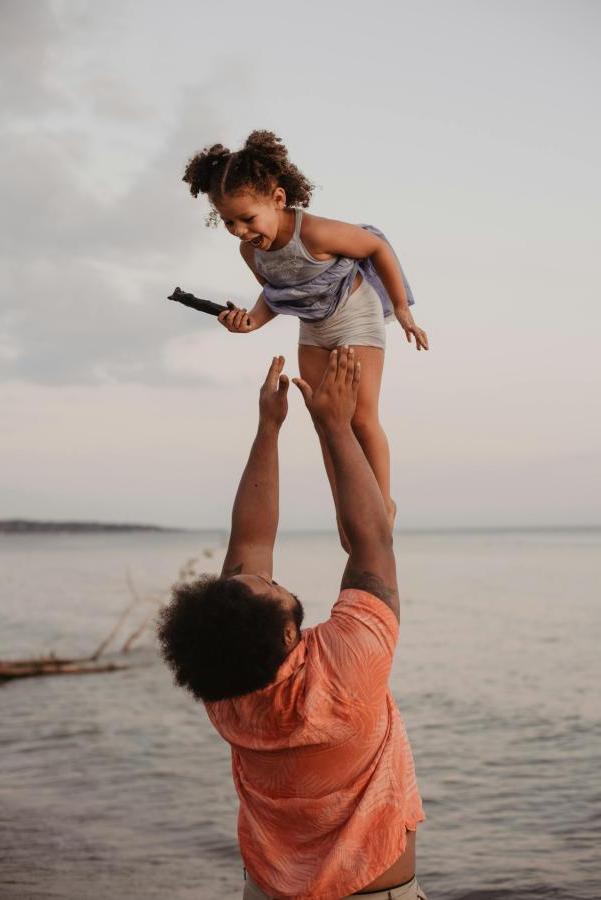 father throwing daughter in the air at beach